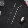 A set of long, thin stainless steel straws and a measuring tool are displayed on a dark surface.