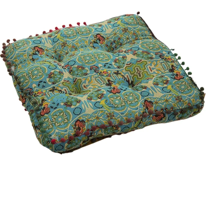 A teal and gold bohemian cotton linen floor cushion with memory foam and decorative fringe.