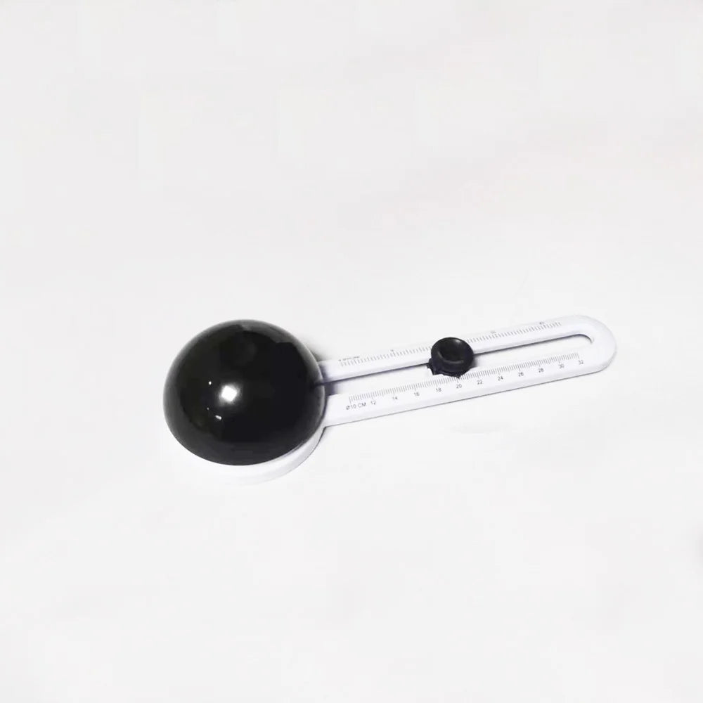 A black circular object with a white scale and markings, likely an adjustable paper cutter.