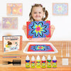 A smiling girl holds a colorful magic draw painting kit with various supplies and a finished fluid art design on a tray.