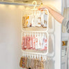 A hand is hanging various folded white and pink cloth items on a multi-clip space-saving laundry drying rack.