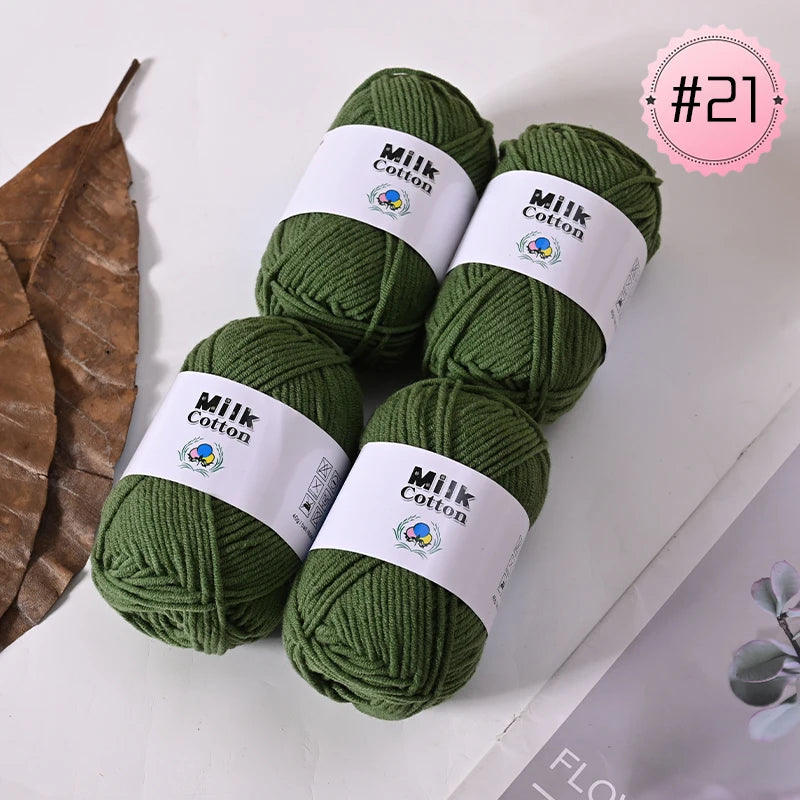 A pile of dark green Milk Cotton yarn balls with white labels on a white surface.