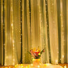Golden sheer curtains decorated with vertical fairy lights and a bouquet of flowers on the floor