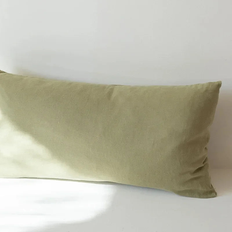 A light olive green linen pillowcase with an envelope closure resting on a white surface.