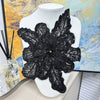 Black floral lace applique patch covered in sequins displayed on a white mannequin.
