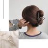 Nahaufnahme eines geometrischen Kreuz-Haarspangenclips, verwendet um ein Haar-Updo zu stylen.