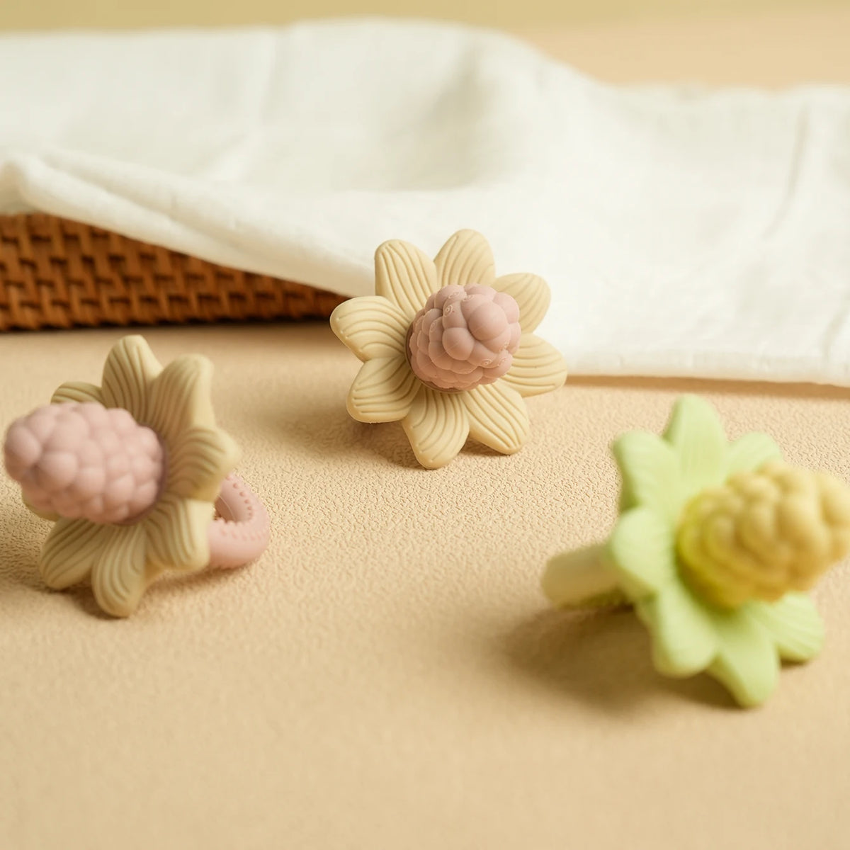 Silicone baby teether toys shaped like flowers and grapes in pink, beige, and green colors