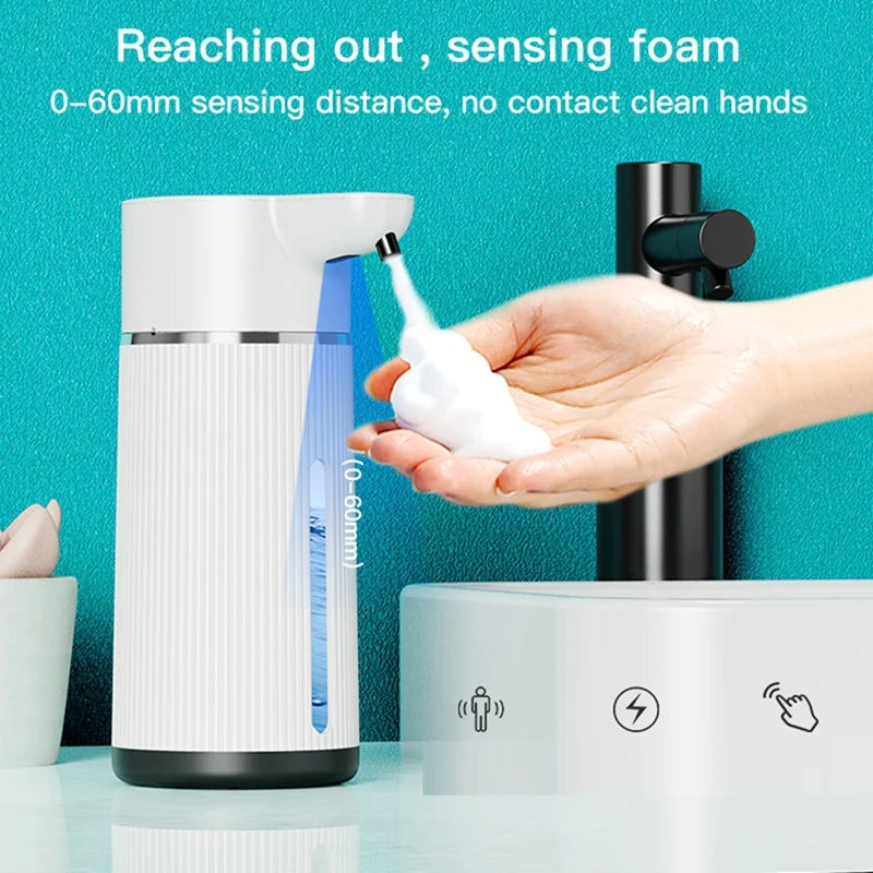 A hand is demonstrating a touchless soap dispenser, showing the foam being dispensed from the device.