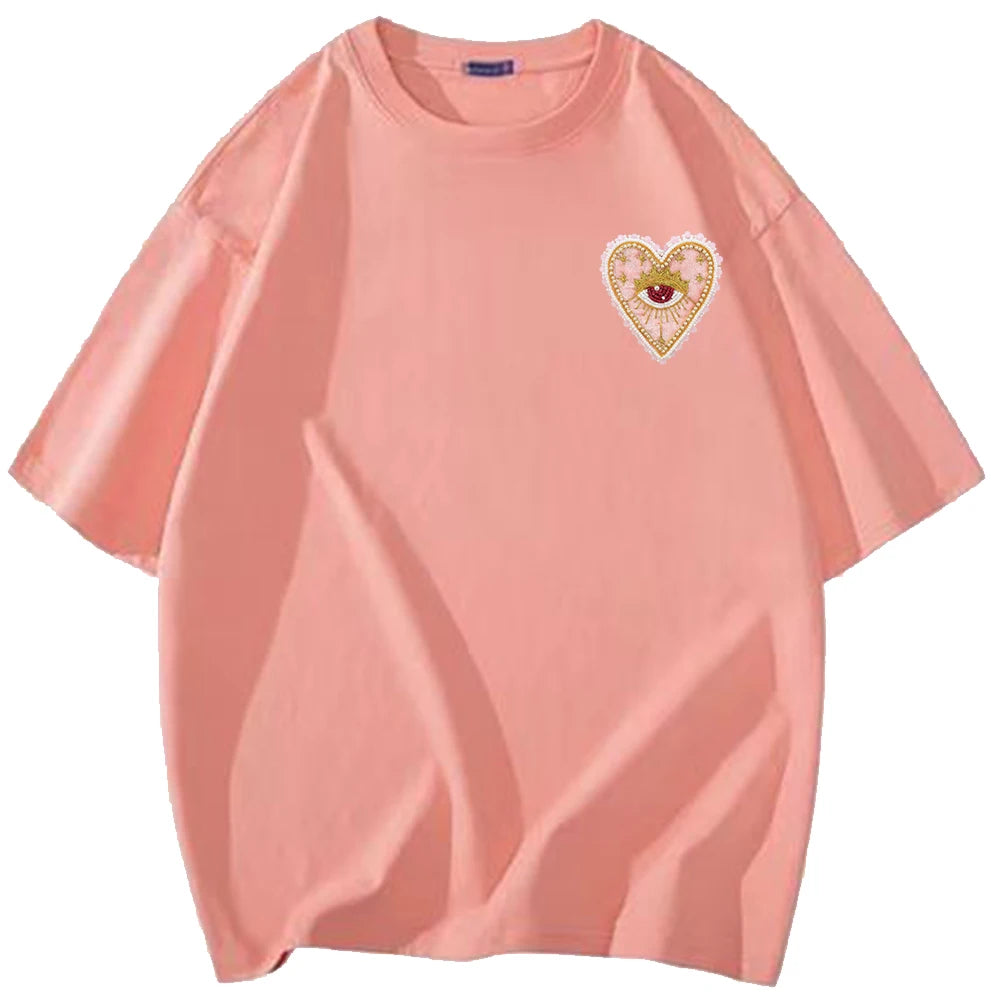 A light peach t-shirt featuring a heart-shaped rhinestone patch design on the chest.