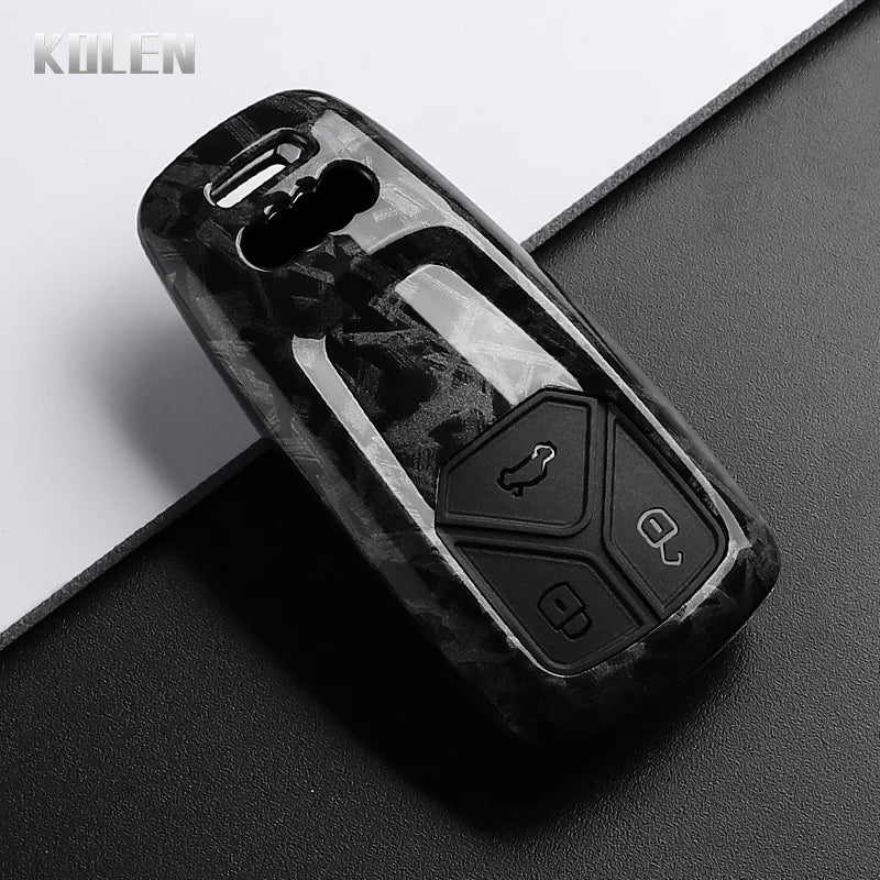 A black carbon fiber style key fob cover for an Audi, shown in a close-up view.