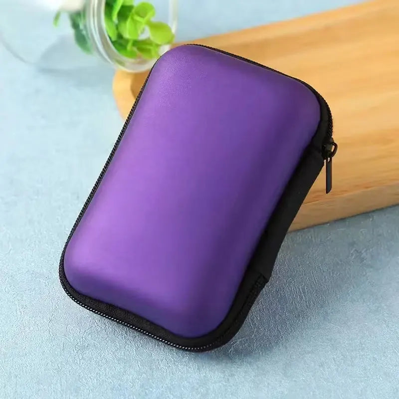 A purple portable electronics organizer pouch with a black zipper rests on a wooden surface.