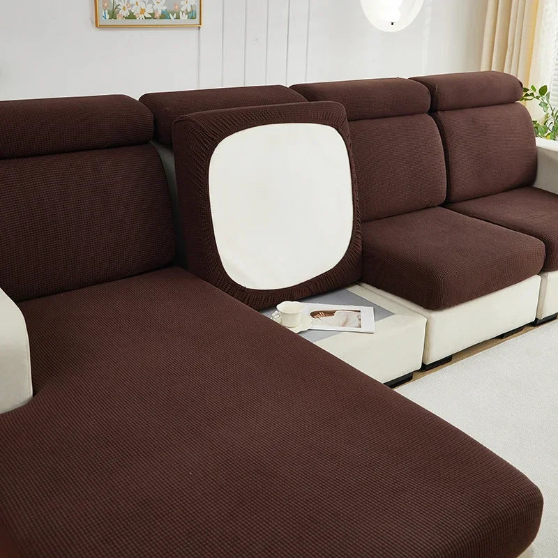 A deep brown Jacquard stretch sofa slipcover with a white back cushion and light-colored frame.