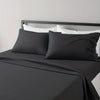 A black microfiber bed sheet set with white pillows and a dark gray headboard.
