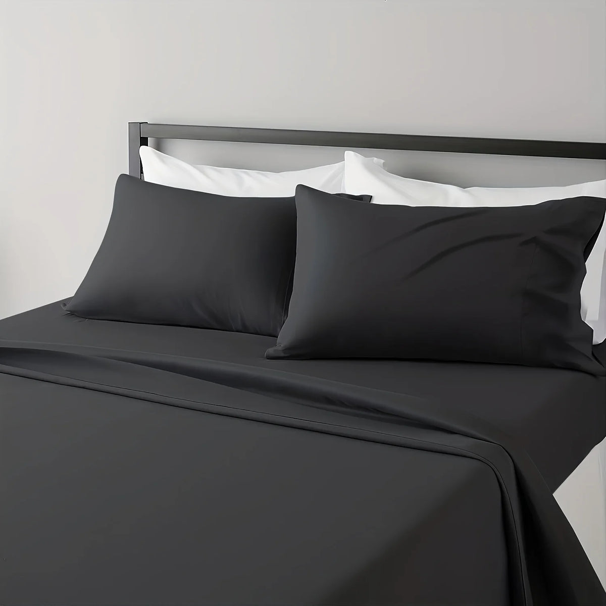 A black microfiber bed sheet set with white pillows and a dark gray headboard.