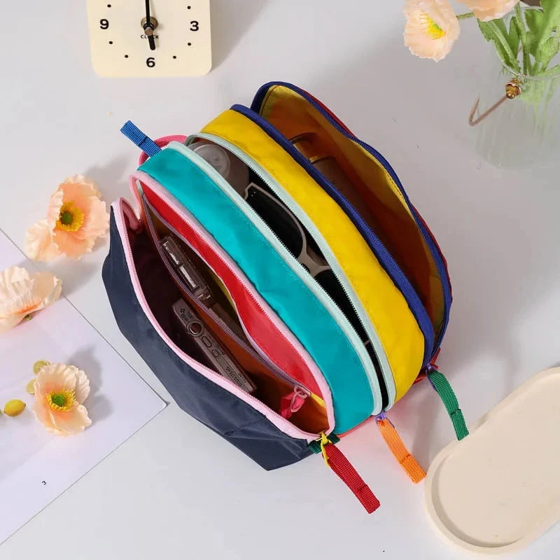 Eine Stapel leichter Reise-Toilettentaschen in verschiedenen Dopaminfarben wie Gelb, Cyan, Pink und Blau.