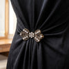 A close-up of a black fabric draped with an ornate gold rhinestone bowknot clip.