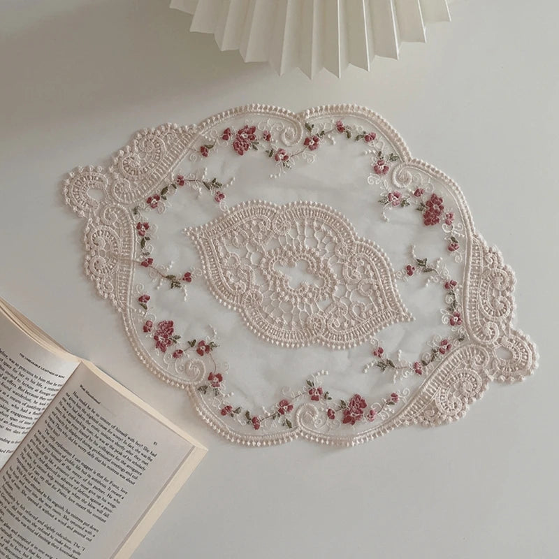 Elegant oval lace embroidered placemat with pink floral embroidery on a white background