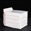 A stack of white padded bubble mailers with self-seal closures is displayed on a dark surface.