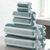 A stack of light blue and white striped bath towels on a gray surface.