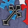 A set of ten vibrant embroidered cross patches in blue, red, and black on a denim fabric background.