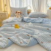 Light blue striped quilt with a playful cartoon print featuring small animals on a bed.