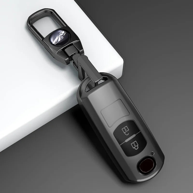 A black TPU car key cover with a metal hook and electronic features is shown on a white surface.