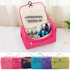 A collection of pink and purple hanging makeup bags for travel and organization.