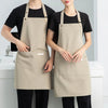 A woman wearing a beige waterproof canvas chef apron over a black shirt and pants.