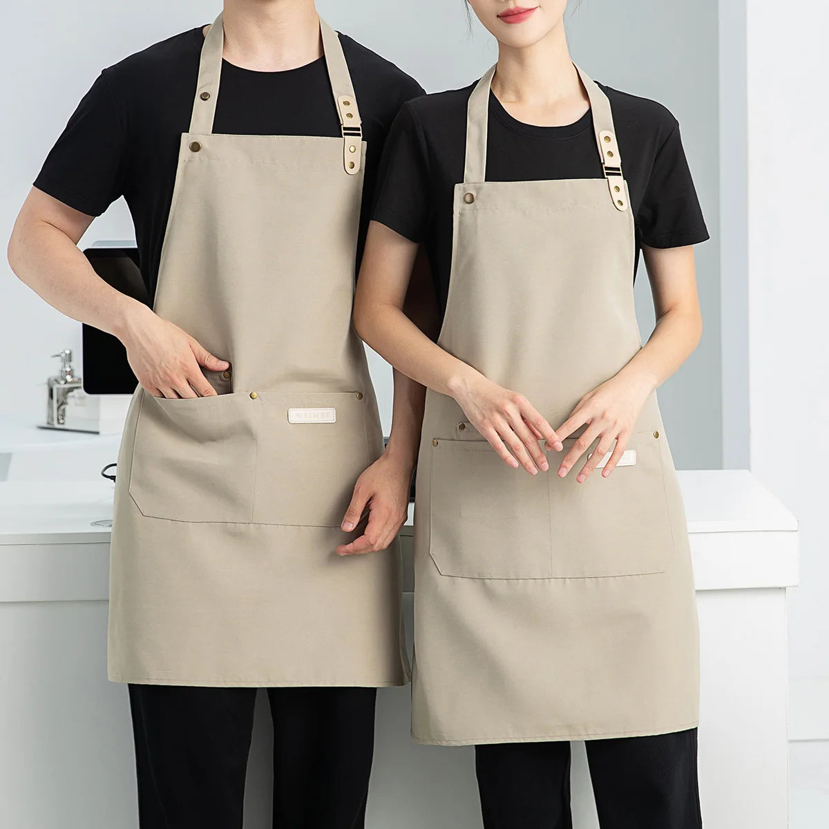 A woman wearing a beige waterproof canvas chef apron over a black shirt and pants.