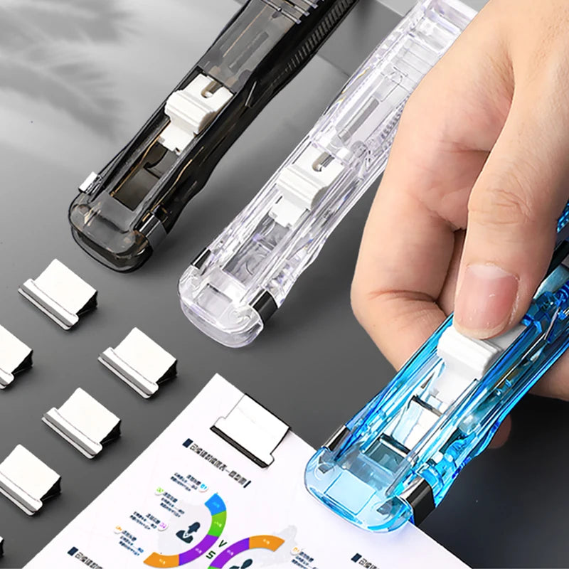 A hand holds a blue reusable push clamp stapler next to several white staples and a paper binder.
