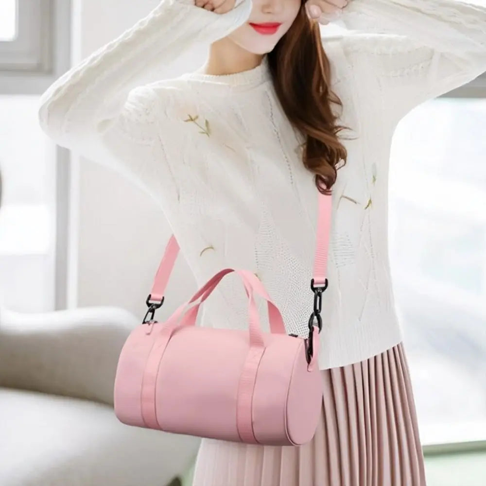 A woman wearing a white sweater holds a pink compact nylon gym bag with an adjustable strap.