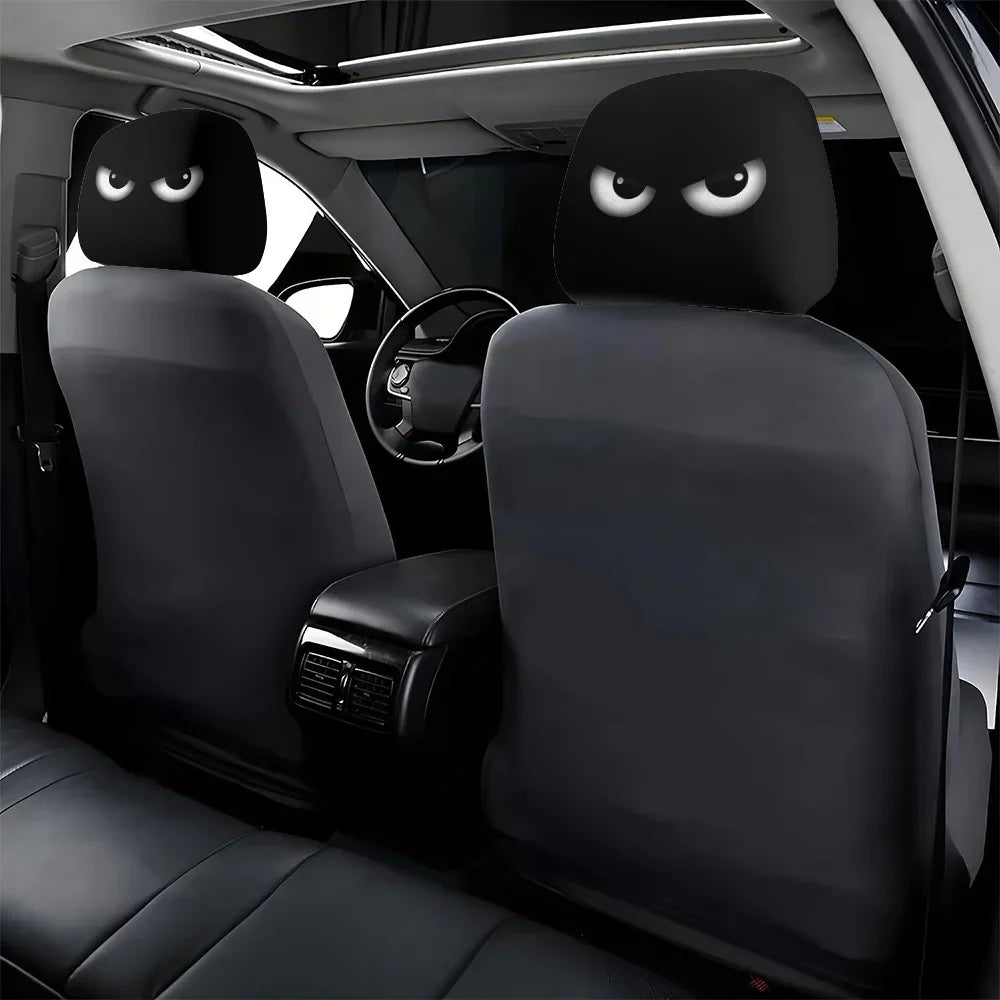 A pair of black car headrest covers with slanted eyes are shown inside a vehicle cabin.