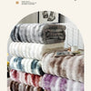 A stack of gradient bubble fleece throw blankets in various shades of gray, white, purple, and brown.