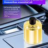 Une bouteille en verre d'huile essentielle d'Osmanthus posée sur une console de voiture sombre.