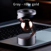 A silver and rose gold magnetic levitating spinning top resting on a laptop keyboard.