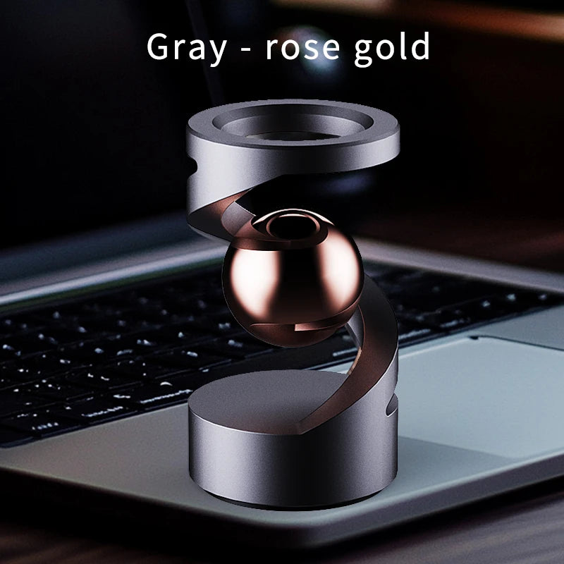 A silver and rose gold magnetic levitating spinning top resting on a laptop keyboard.