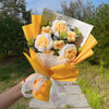 Sträußchen aus handgefertigten Häkel-Sonnenblumen, verpackt in gelbem Papier und mit durchscheinendem Band gebunden.