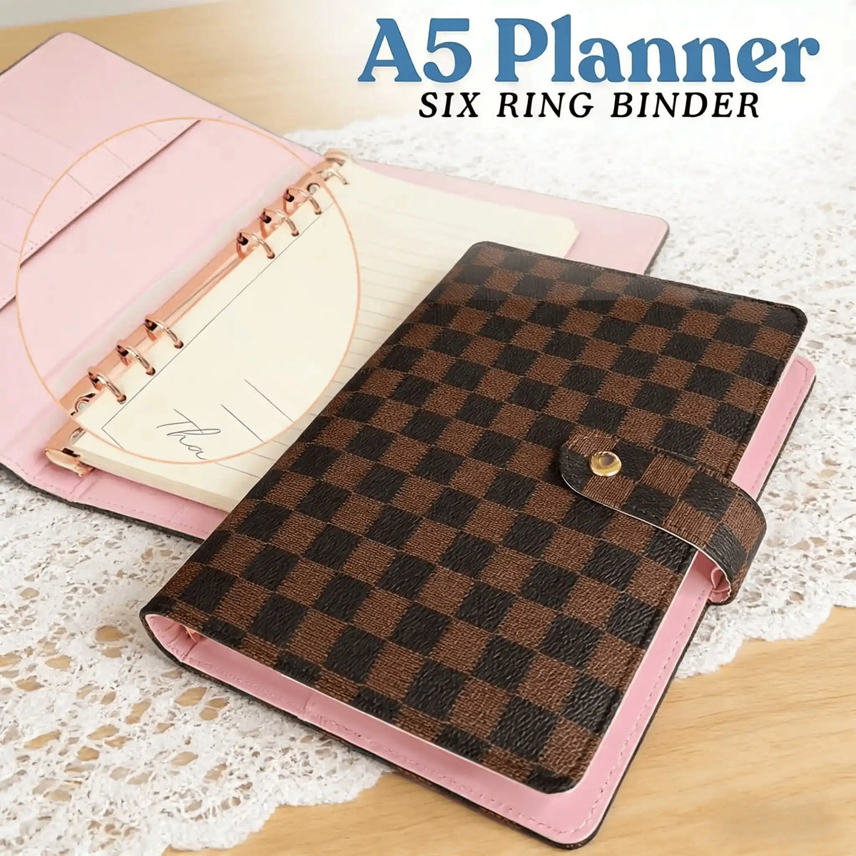 A pink A5 planner with a brown checkered binder cover and a white page inside.