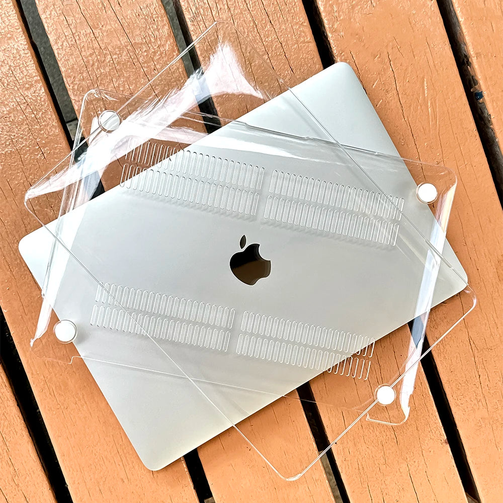 A clear protective case is placed over a silver MacBook, resting on a wooden surface.