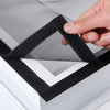 A hand is folding a black self-adhesive window mosquito net screen over a white frame.