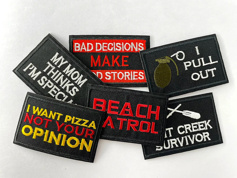 A collection of black embroidered iron-on patches with humorous text like BAD DECISIONS MAKE STORIES and I PULL OUT