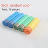 Five rolls of random colored drawstring trash bags with handles laid out on a white surface.