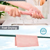 Hands are squeezing a pink reusable microfiber cleaning cloth under running water, demonstrating fast drying.