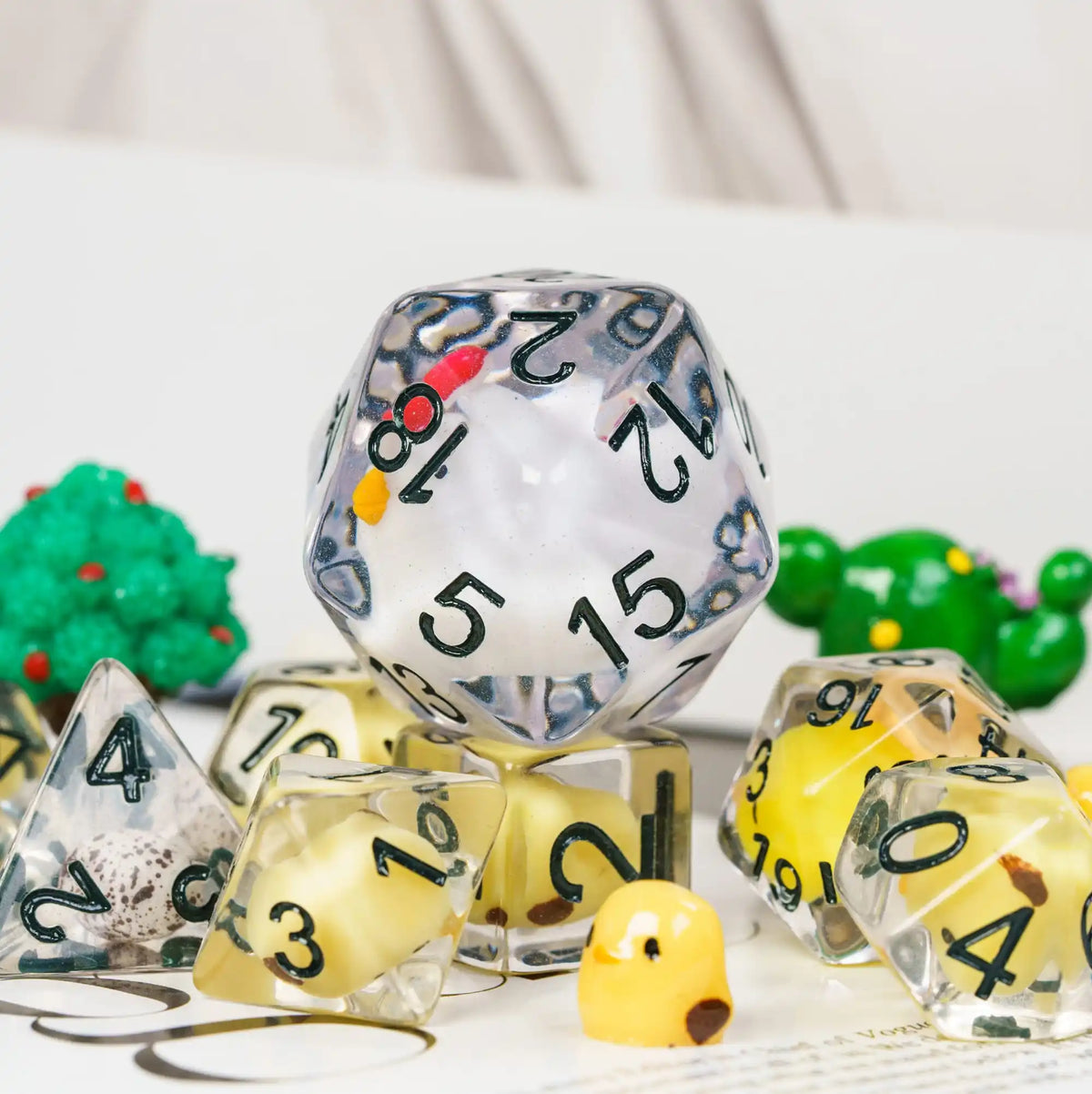 A collection of clear resin dice and a yellow animal figurine are displayed on a white surface.