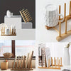 A set of eco-friendly bamboo dish drying racks and white ceramic mugs displayed on a wooden surface.
