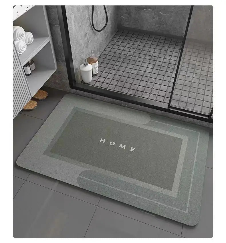 A rectangular gray bath mat with a non-slip rubber base is placed on a dark tiled floor inside a shower enclosure.