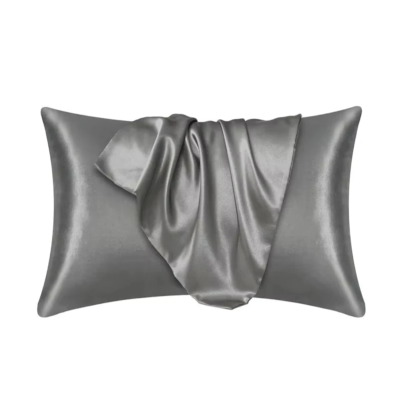 Funda de almohada de seda satinada gris suave y elegantemente drapeada.