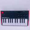 A black AKAI MPK Mini professional MIDI keyboard controller with 25 keys, drum pads, and knobs.