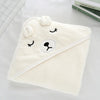 A soft, cream-colored hooded baby bath towel with a cute bear face design.