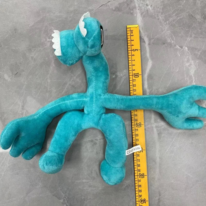 A teal plush toy of an Opila bird from Garten of BanBan is displayed next to a yellow ruler.